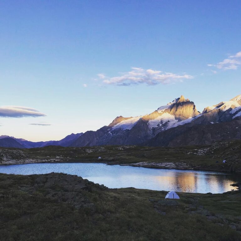 Bivouac sous tente au bord d'un lac de montagne au coucher du soleil