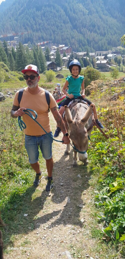 Un enfant à dos d'âne accompagné sur un sentier de montagne